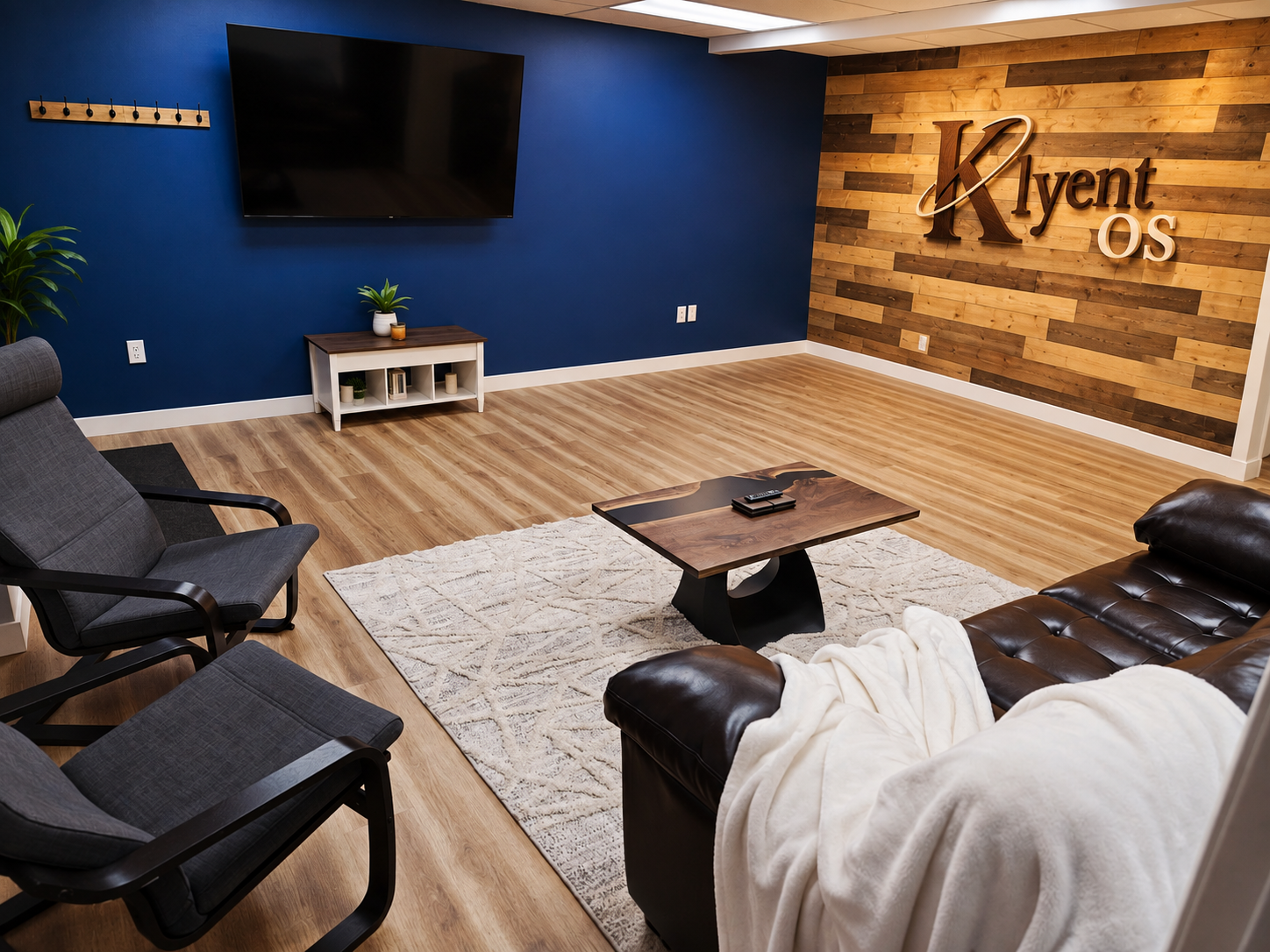 The KLYENT AI Builder Lab lounge: a workspace with a live-edge coffee table, seating, and the KLYENT logo on a wood-plank wall.